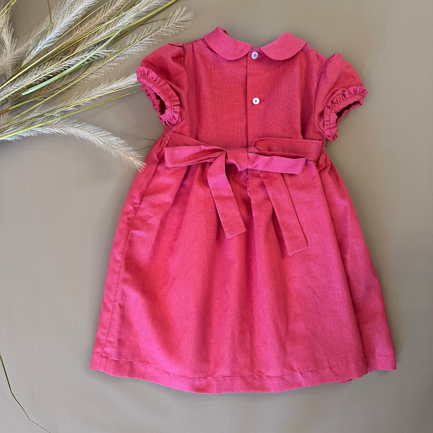 Abito in punto smock color fragola: eleganza e lavorazione raffinata